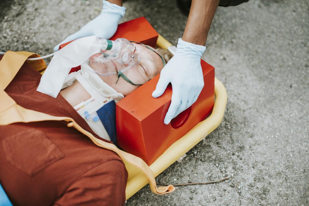 Person lying down on a stretcher with head immobilizer and neck collar. Items from a first aid and trauma kit are being used.