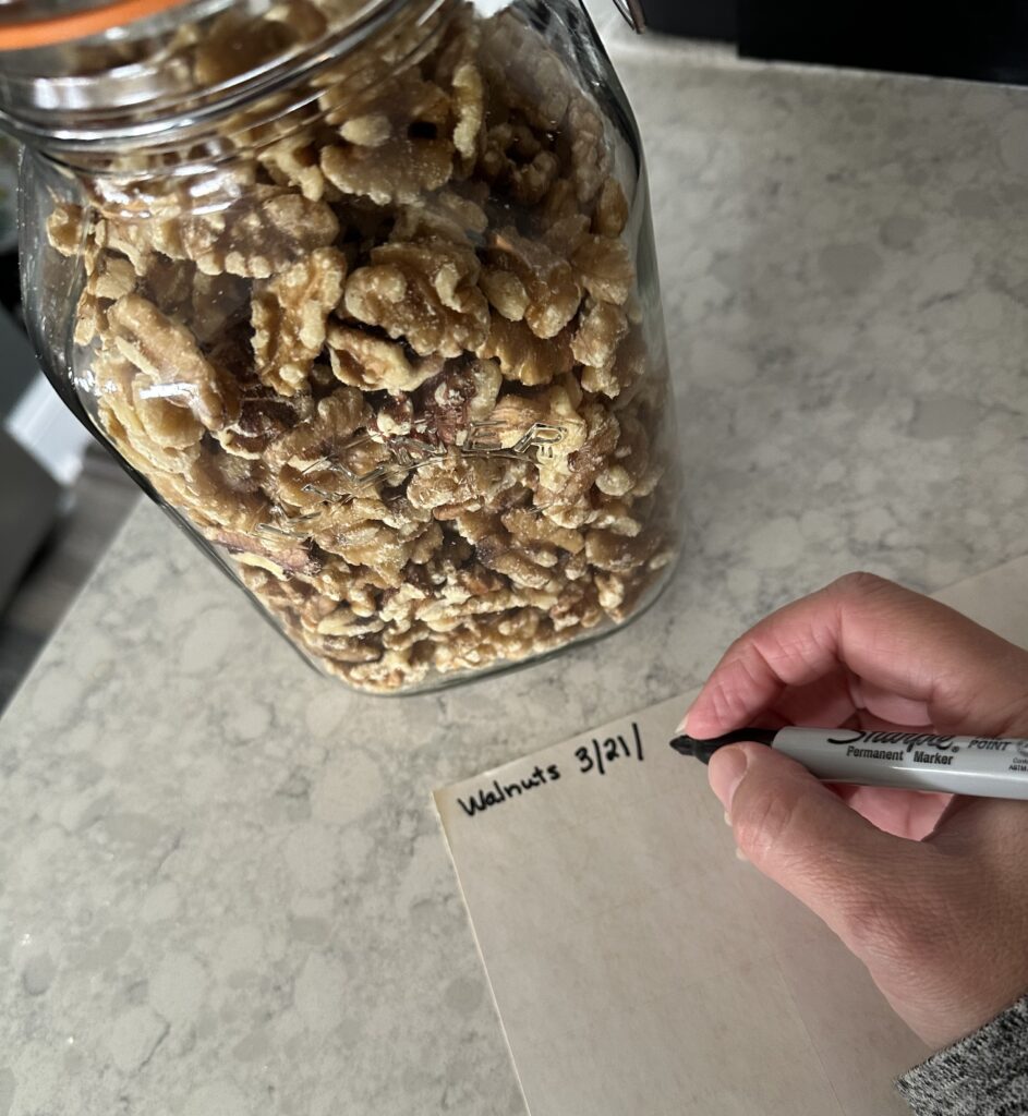 Person labeling a jar of walnuts.