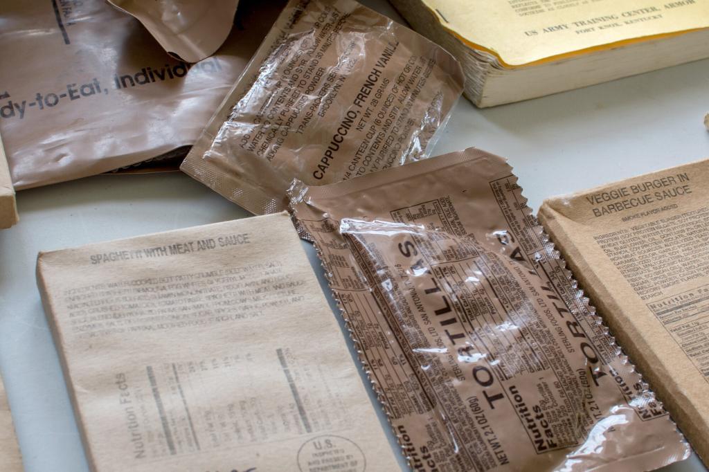Image of a variety of MRE's such as spaghetti and meatballs, cappuccino and a veggie burger. 