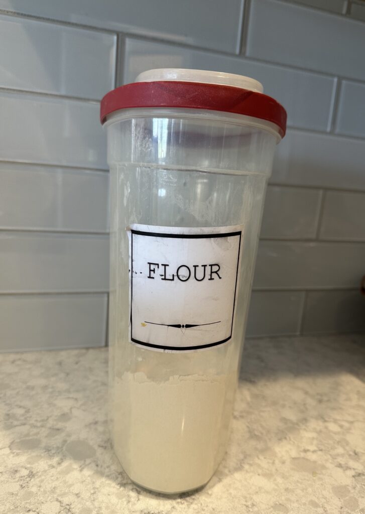 Photo of flour in an plastic container for storage.