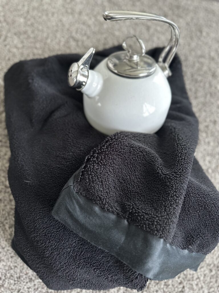 Photo of a water kettle and blanket.