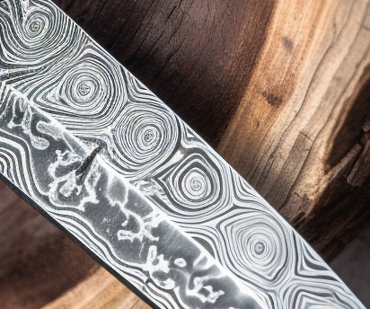 Close up photo of the swirling patterns on a Damascus knife blade.