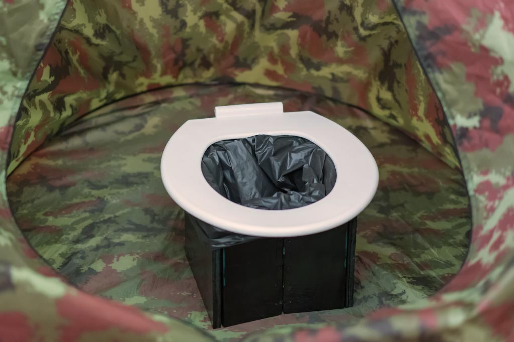 Photo of a portable toilet inside a tent for privacy. One of the easy off grid bathroom ideas.