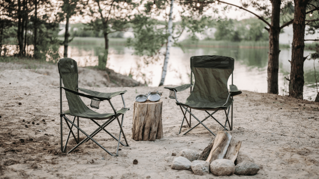 Photo of 2 camping chairs next to a lake with some of the best survival cookware pans resting on a log.